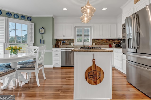 kitchen featuring light wood-style floors, appliances with stainless steel finishes, white cabinetry, crown molding, and a center island