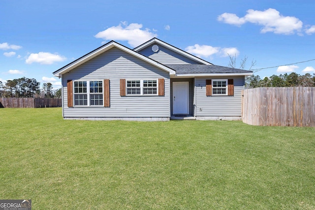 view of front of home with a shingled roof, a front lawn, and fence