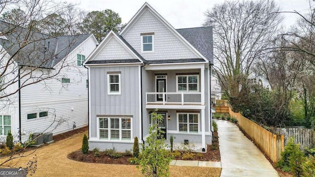 view of front facade featuring a standing seam roof, fence, board and batten siding, metal roof, and a balcony