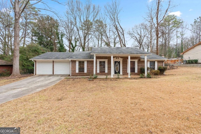 view of front facade featuring a front lawn, driveway, covered porch, a garage, and brick siding