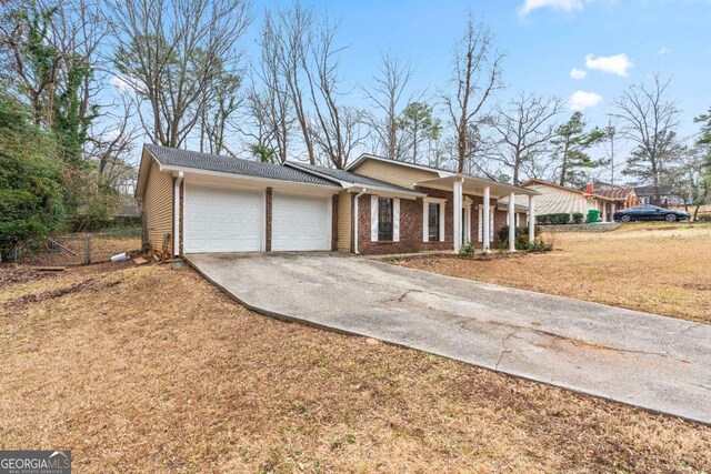 ranch-style house with a front lawn, an attached garage, brick siding, and driveway