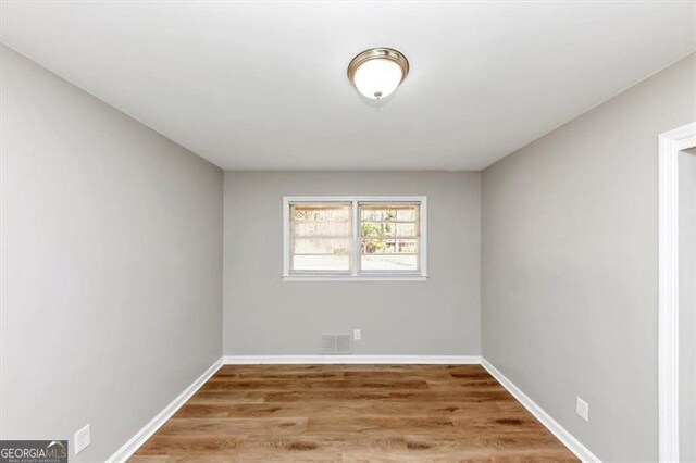 spare room featuring visible vents, baseboards, and wood finished floors