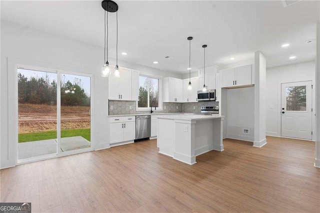 kitchen featuring backsplash, appliances with stainless steel finishes, white cabinetry, and light wood-type flooring