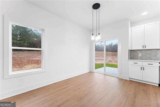 unfurnished dining area with recessed lighting, baseboards, a notable chandelier, and light wood finished floors