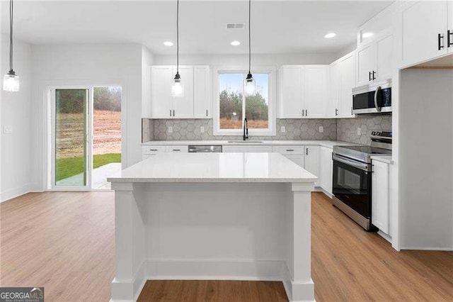 kitchen with visible vents, light wood-style flooring, a sink, a kitchen island, and appliances with stainless steel finishes