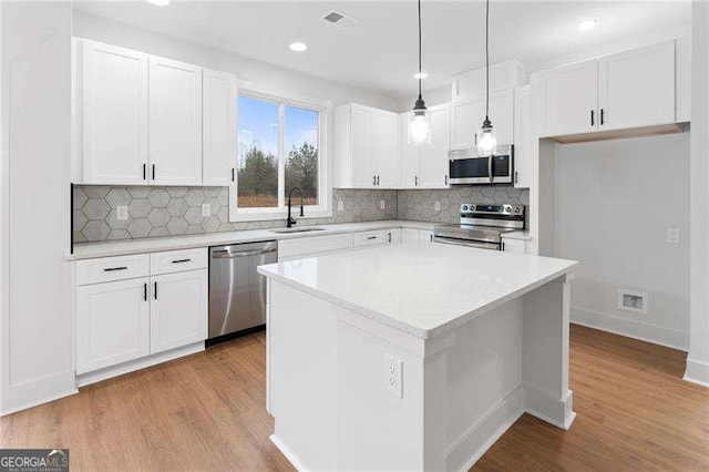 kitchen with visible vents, a sink, hanging light fixtures, appliances with stainless steel finishes, and white cabinetry