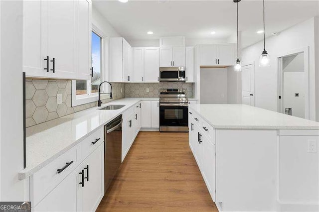 kitchen with a sink, a center island, white cabinetry, and stainless steel appliances