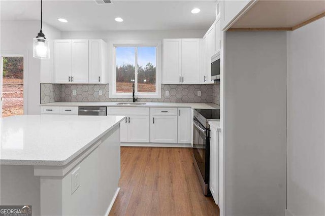 kitchen with light wood-style flooring, a sink, stainless steel appliances, white cabinets, and light countertops