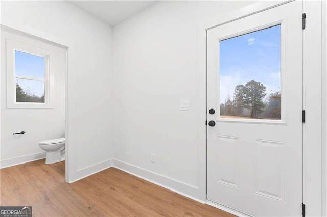 doorway to outside featuring baseboards and light wood-type flooring