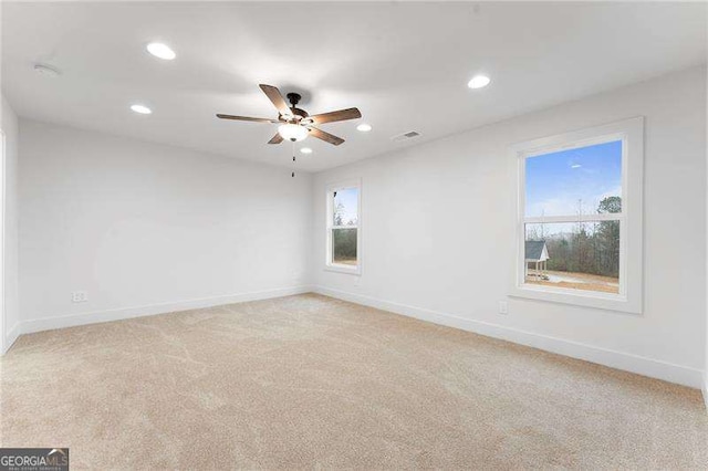 spare room featuring light carpet, recessed lighting, and baseboards