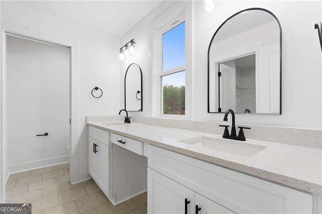 bathroom featuring a sink, baseboards, and double vanity