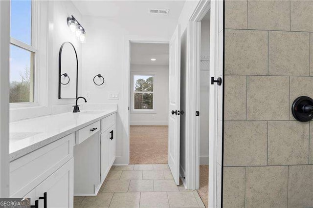 bathroom with a sink, visible vents, double vanity, and tile patterned floors