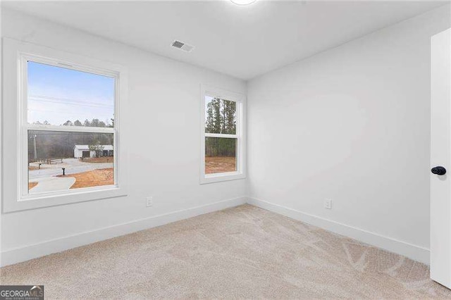 unfurnished room with a wealth of natural light, visible vents, baseboards, and carpet flooring