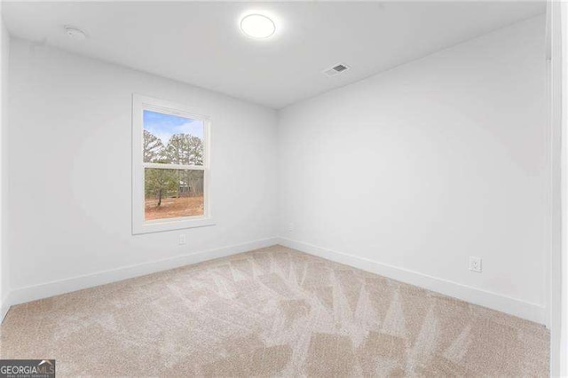 carpeted spare room featuring visible vents and baseboards