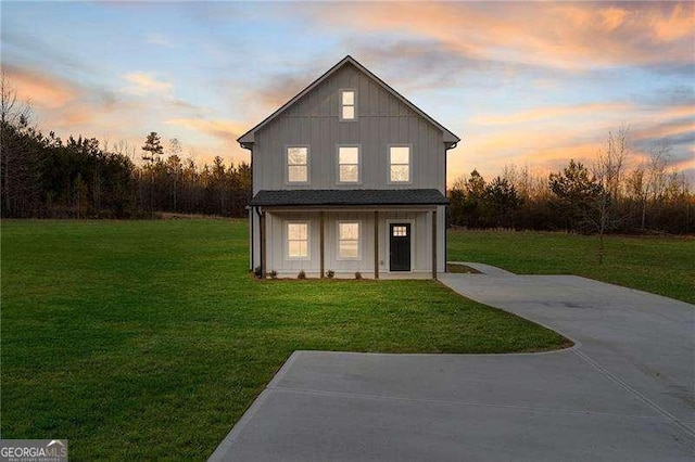 property exterior at dusk with a lawn and board and batten siding