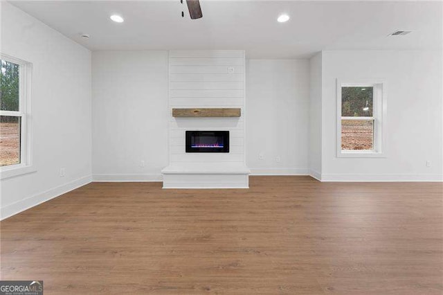 unfurnished living room featuring a wealth of natural light, visible vents, and wood finished floors