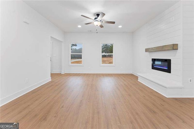 unfurnished living room with a fireplace, baseboards, and wood finished floors