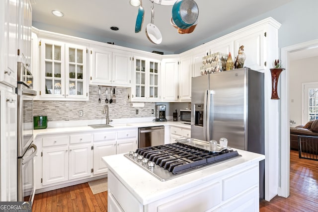 kitchen featuring light wood-style flooring, a sink, a kitchen island, white cabinetry, and appliances with stainless steel finishes