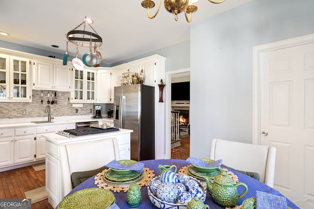 kitchen with dark wood-style floors, a sink, decorative backsplash, light countertops, and stainless steel refrigerator with ice dispenser