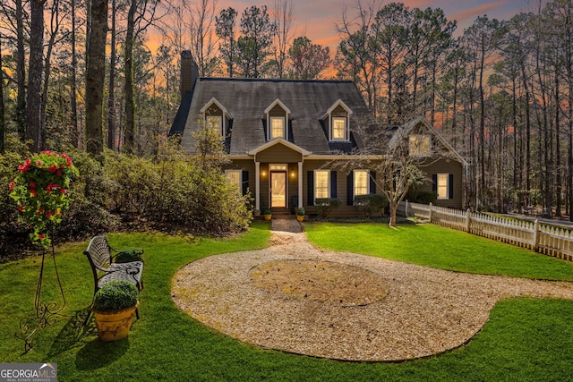 cape cod-style house with gravel driveway, a front lawn, and fence