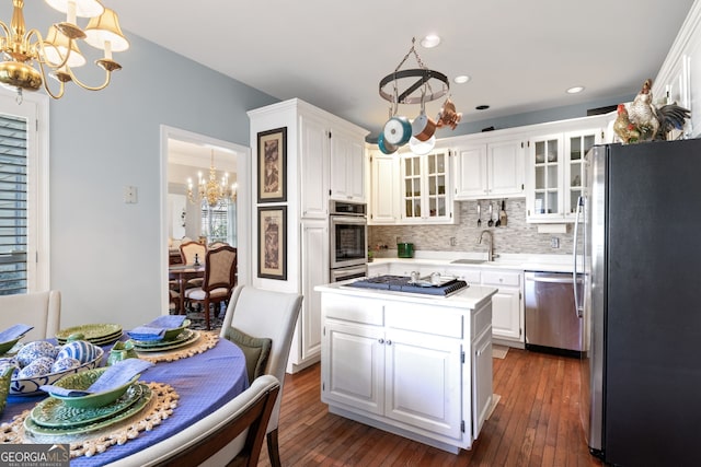 kitchen featuring a notable chandelier, a kitchen island, white cabinetry, appliances with stainless steel finishes, and light countertops