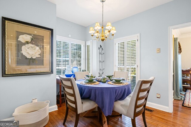 dining room featuring a chandelier, baseboards, visible vents, and hardwood / wood-style floors