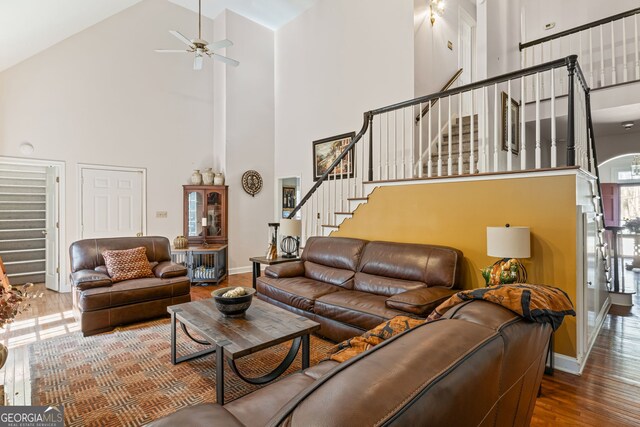 living area with stairway, a high ceiling, baseboards, and wood finished floors