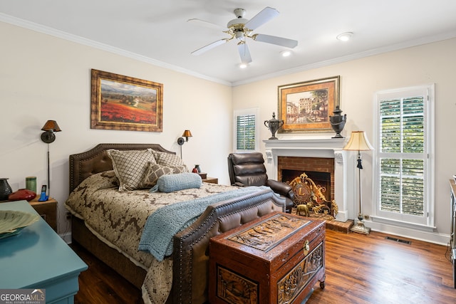 bedroom with visible vents, a brick fireplace, crown molding, and wood finished floors