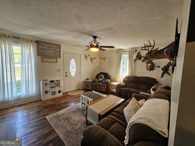 living area with a textured ceiling, dark wood-style floors, visible vents, and ceiling fan