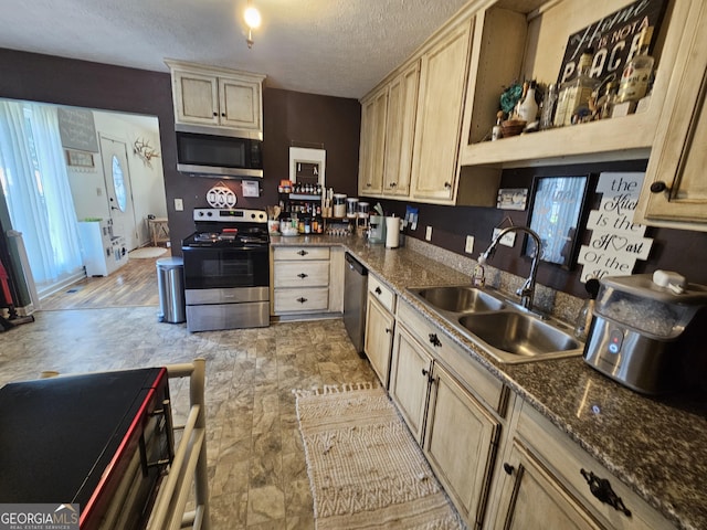 kitchen with dark countertops, appliances with stainless steel finishes, a textured ceiling, and a sink