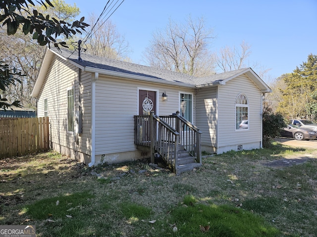 view of front of home featuring a shingled roof, fence, and crawl space