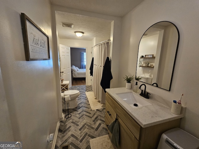 bathroom featuring visible vents, toilet, vanity, brick floor, and a textured ceiling