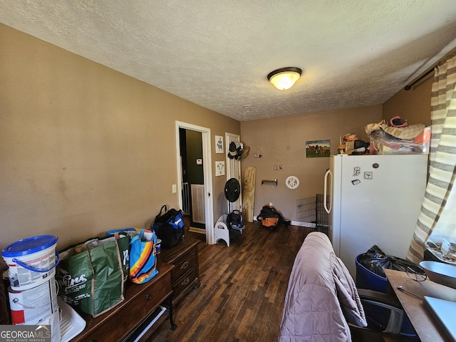 bedroom with wood finished floors, freestanding refrigerator, and a textured ceiling