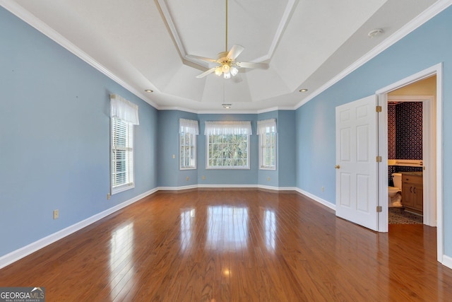 unfurnished room featuring ceiling fan, baseboards, a tray ceiling, ornamental molding, and wood finished floors