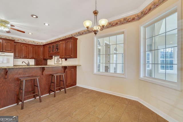 kitchen with oven, a kitchen bar, baseboards, and ornamental molding