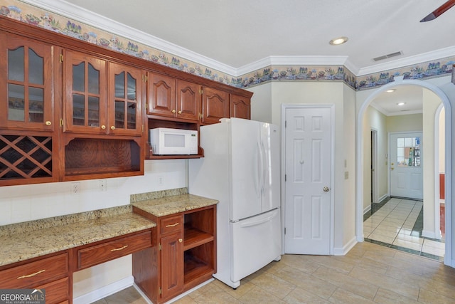 kitchen featuring white appliances, glass insert cabinets, arched walkways, and light stone countertops