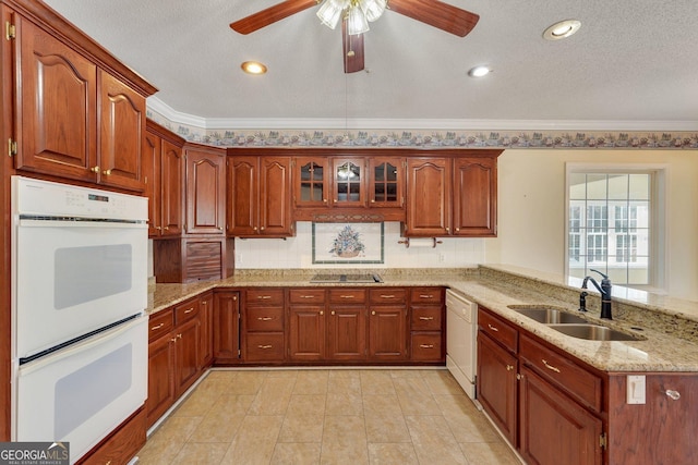 kitchen featuring a sink, white appliances, a peninsula, crown molding, and light stone countertops