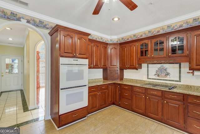 kitchen featuring visible vents, arched walkways, decorative backsplash, white double oven, and black electric stovetop