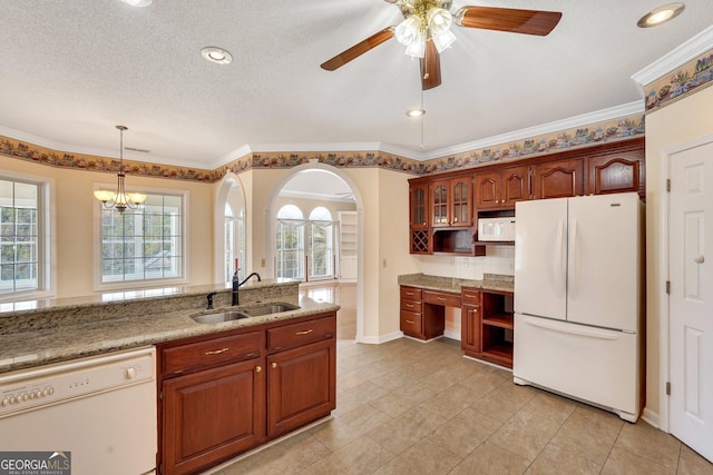 kitchen featuring white appliances, light stone countertops, built in study area, a sink, and glass insert cabinets