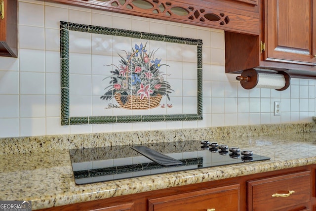 details featuring light stone counters, black electric stovetop, and brown cabinetry