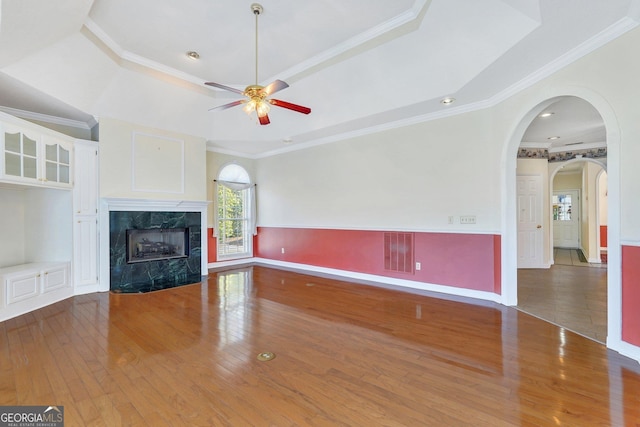 unfurnished living room with visible vents, a tray ceiling, ornamental molding, hardwood / wood-style floors, and a premium fireplace