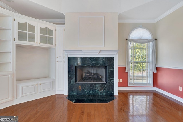 unfurnished living room with hardwood / wood-style floors, baseboards, ornamental molding, and a fireplace