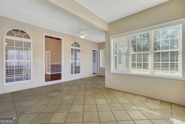 tiled spare room with a ceiling fan