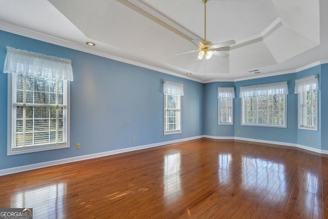 unfurnished room featuring a raised ceiling, ornamental molding, hardwood / wood-style floors, baseboards, and ceiling fan