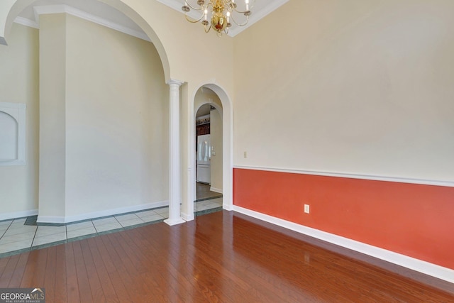 empty room with ornamental molding, hardwood / wood-style floors, arched walkways, decorative columns, and baseboards