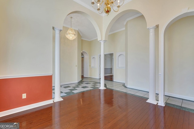 unfurnished room with baseboards, a high ceiling, hardwood / wood-style floors, and ornamental molding