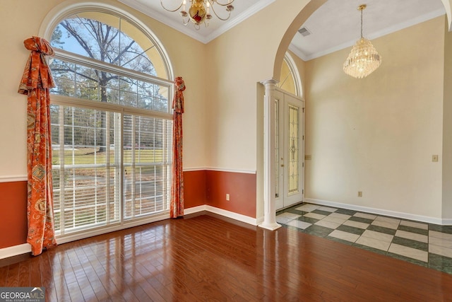 foyer featuring baseboards, a chandelier, hardwood / wood-style floors, ornamental molding, and arched walkways