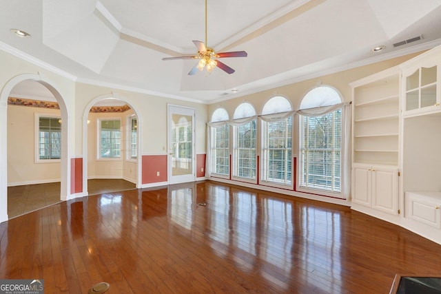 unfurnished room featuring visible vents, a tray ceiling, ceiling fan, hardwood / wood-style flooring, and crown molding