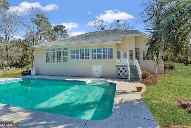 back of house with a patio, a yard, an outdoor pool, and stucco siding