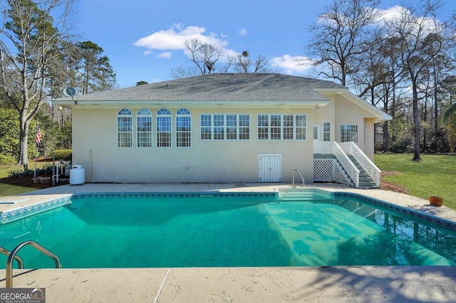 back of house featuring stairway, stucco siding, and an outdoor pool